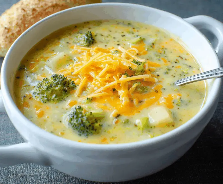 Creamy broccoli, potato, and cheese soup in a bowl, garnished with fresh herbs and served with crusty bread
