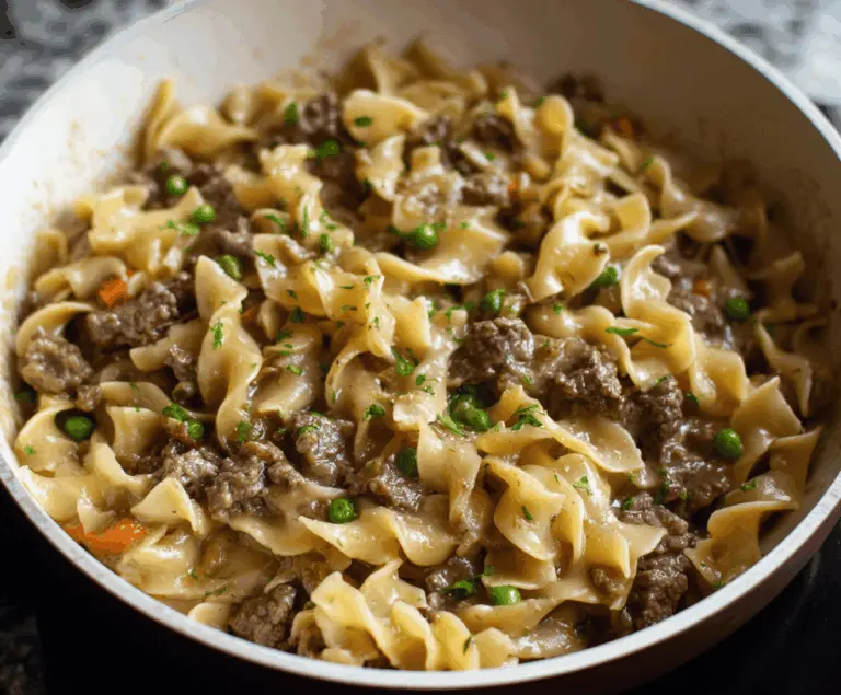 Delicious homemade stovetop beef and noodles served in a white bowl with fresh herbs and vegetables