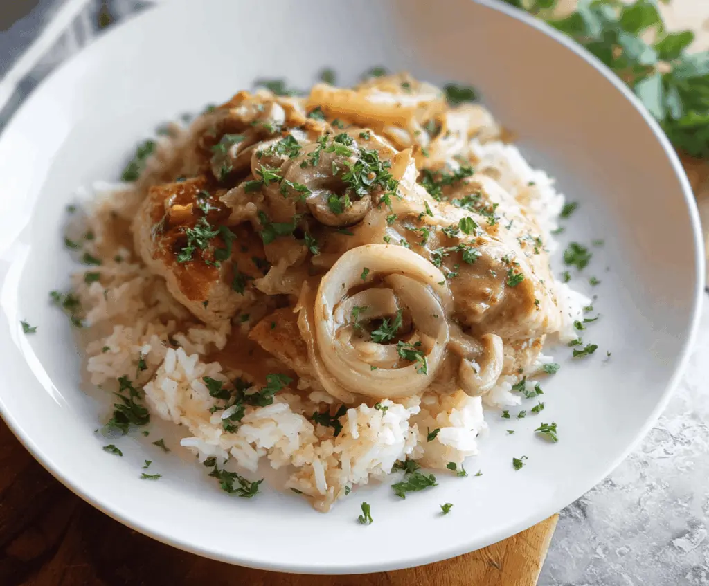 Delicious smothered chicken served over fluffy rice with savory gravy and fresh herbs