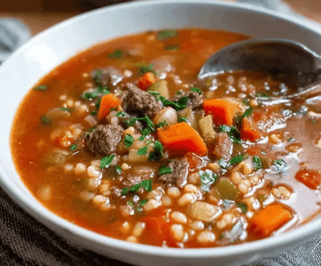 Hearty vegetable beef soup with tender beef chunks, colorful vegetables, and fresh herbs in a bowl