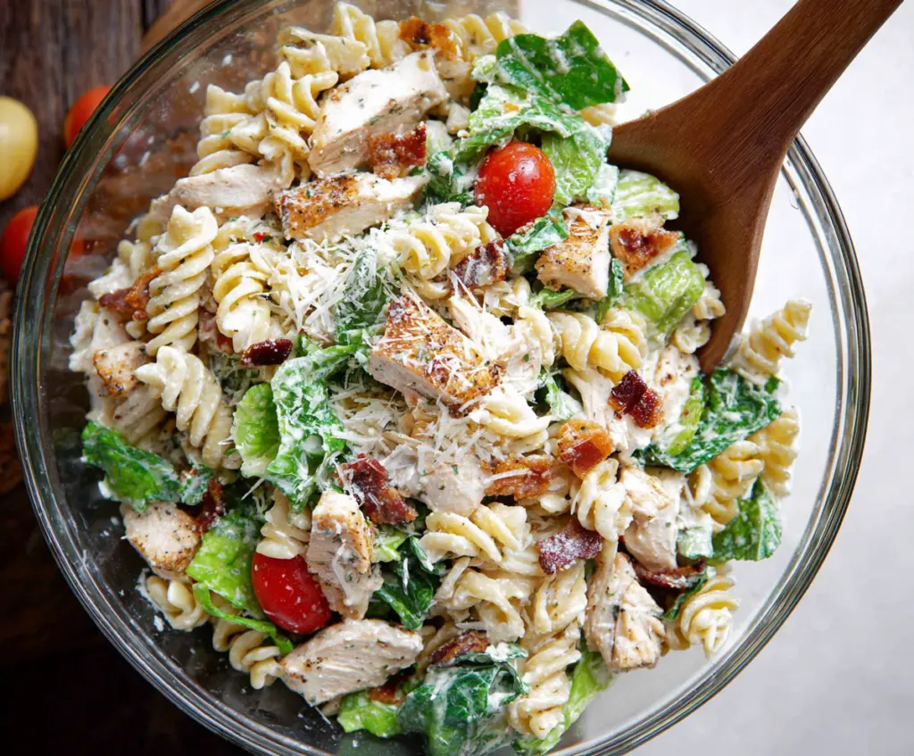 Fresh Chicken Caesar Pasta Salad with romaine lettuce, grilled chicken, and parmesan cheese in a colorful bowl.