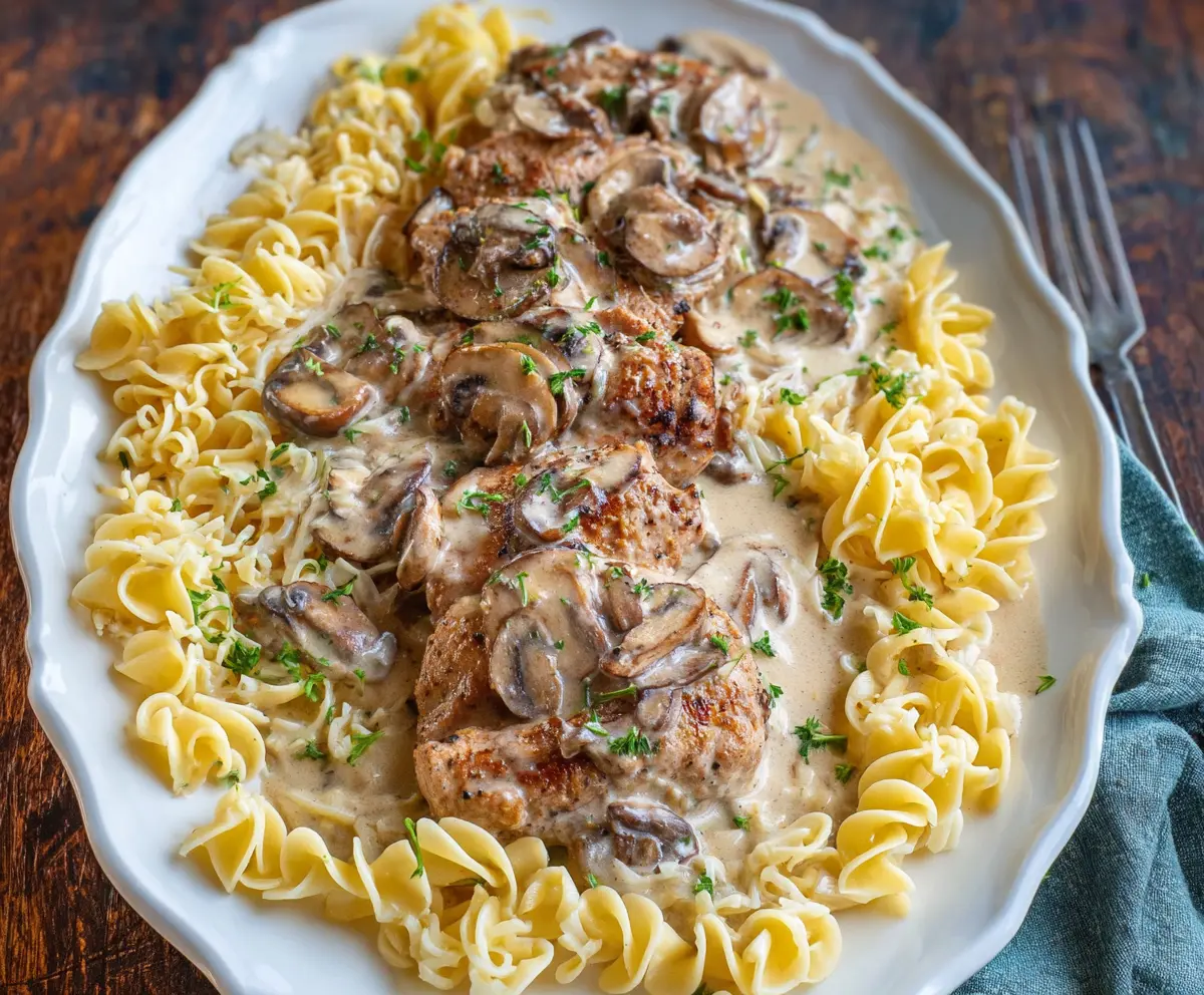 Delicious pork tenderloin served with creamy mushroom sauce and pasta, perfect for a hearty dinner.