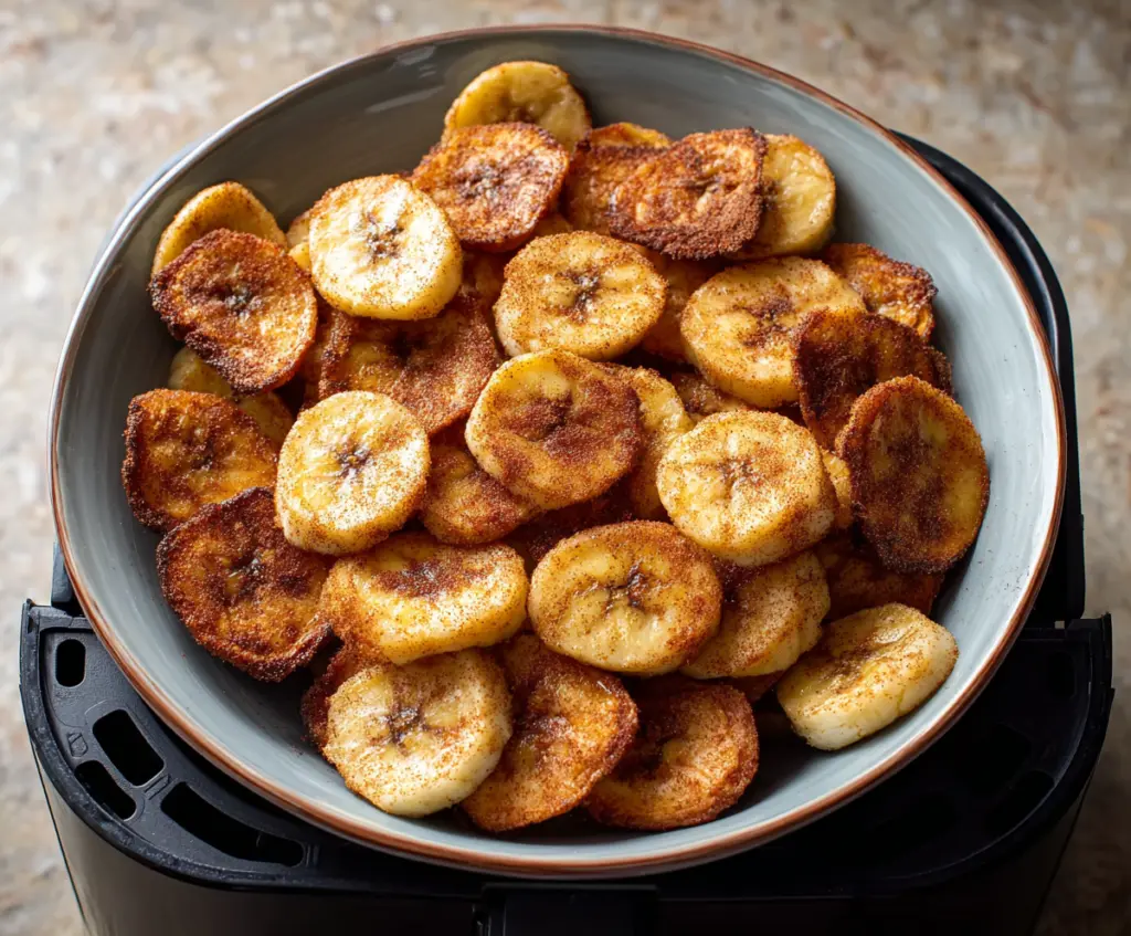 Golden crispy air fryer cinnamon banana chips served on a plate, perfect healthy snack.