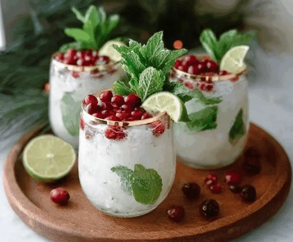 Glass of White Christmas Mojitos with mint leaves and lime slices on a festive holiday table.