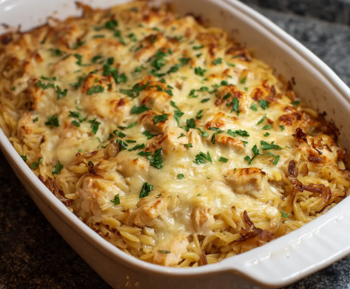 Delicious French Onion Chicken Orzo Casserole in a baking dish garnished with herbs.